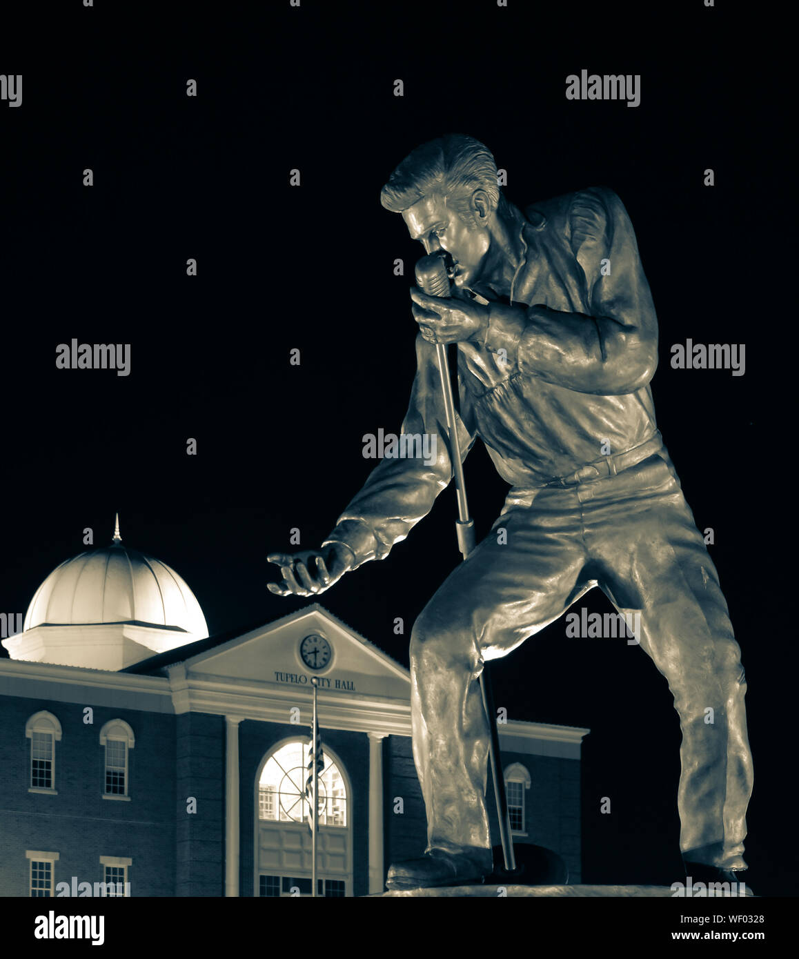 Elvis Presley Statue in Bronze pose mit Mikrofon und ausgestreckte Hand, in der Nacht durch den Tupelo Rathaus in Tupelo, MS, USA, in Selen Ton Stockfoto