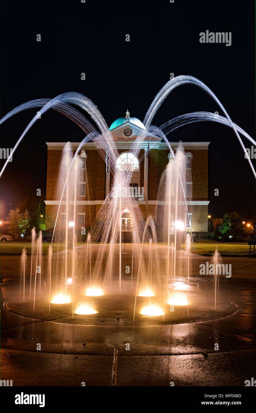 Hier mal einen Blick auf Tupelo Rathaus Gebäude mit Tülle Brunnen mit Beleuchtung im Vordergrund, in Elvis Heimatstadt, Tupelo, MS, USA Stockfoto