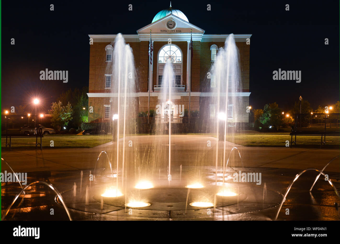 Hier mal einen Blick auf Tupelo Rathaus Gebäude mit Tülle Brunnen mit Beleuchtung im Vordergrund, in Elvis Heimatstadt, Tupelo, MS, USA Stockfoto