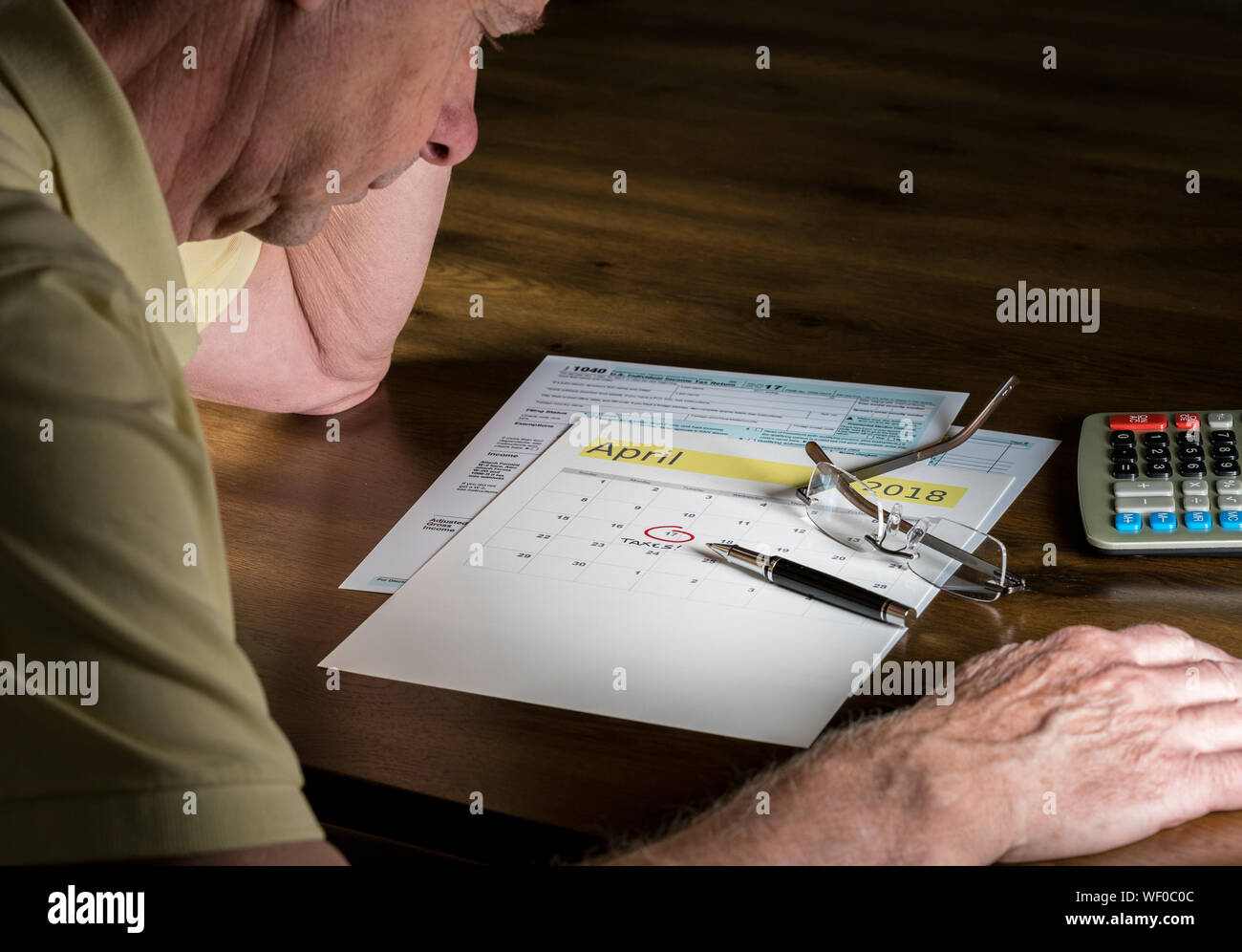 Älterer Mann mit Kugelschreiber und Kalender auf Tabelle Stockfoto