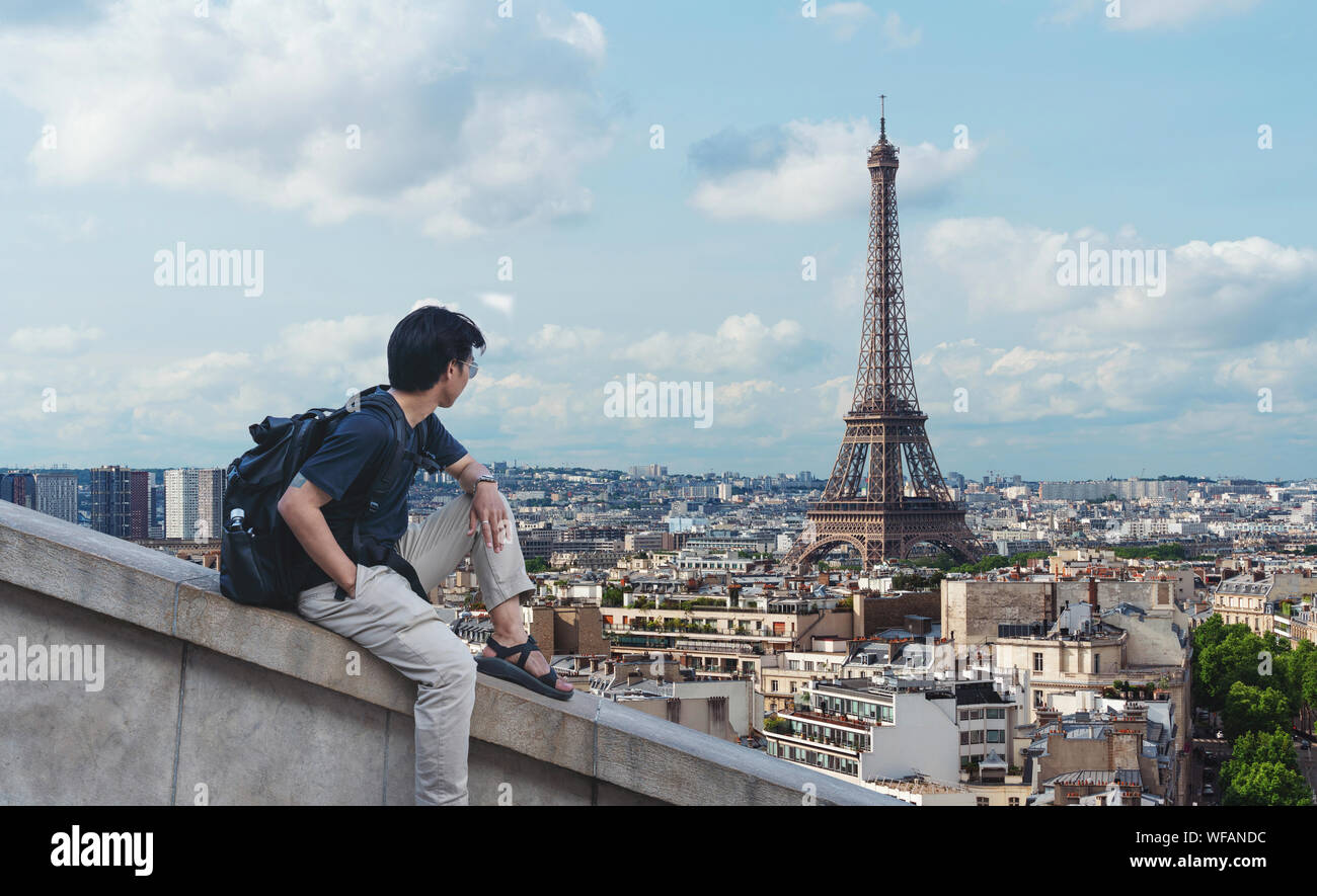 Ein Mann mit Rucksack am Eiffelturm suchen, Wahrzeichen und Reiseziel in Paris, Frankreich Stockfoto