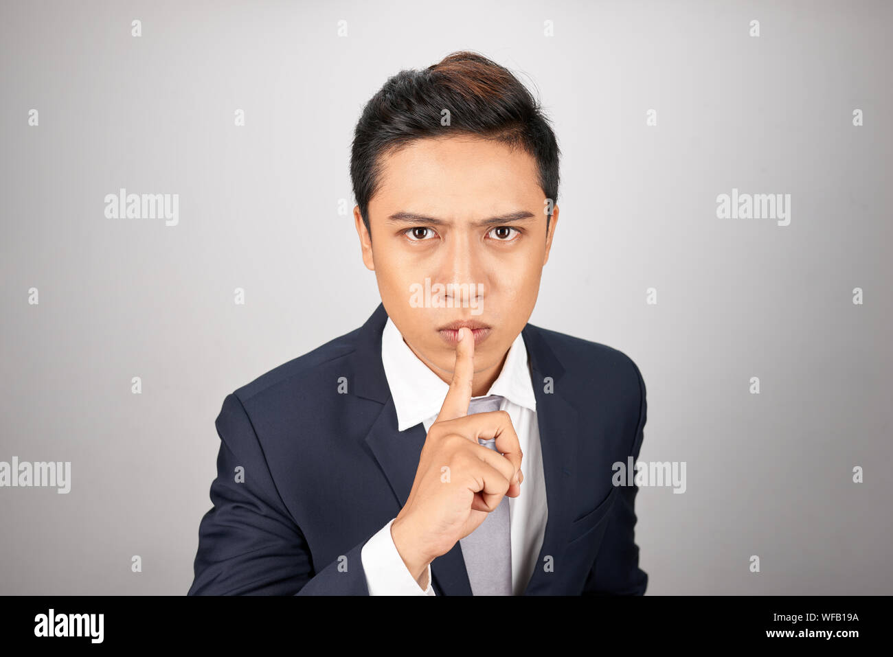 Junge asiatische Geschäftsmann, ein Zeichen der Stille Geste die Finger im Mund Stockfoto