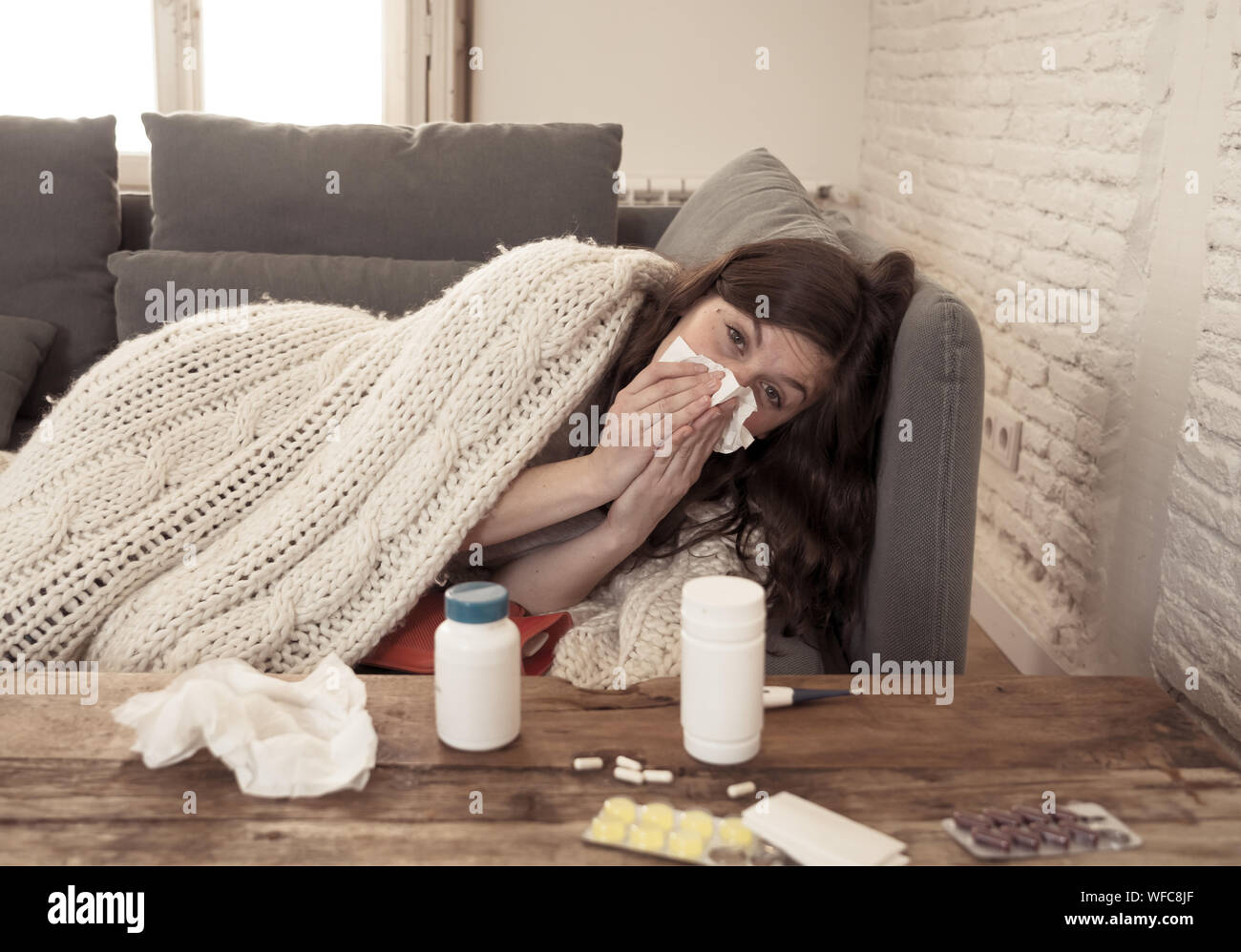 Kranke Frau auf Sofa Niesen und ihre Nase weht mit Allergie, Heuschnupfen oder kalten Unwohlsein, Müdigkeit unruhig und nicht in der Lage, um zur Arbeit zu gehen. Li Stockfoto