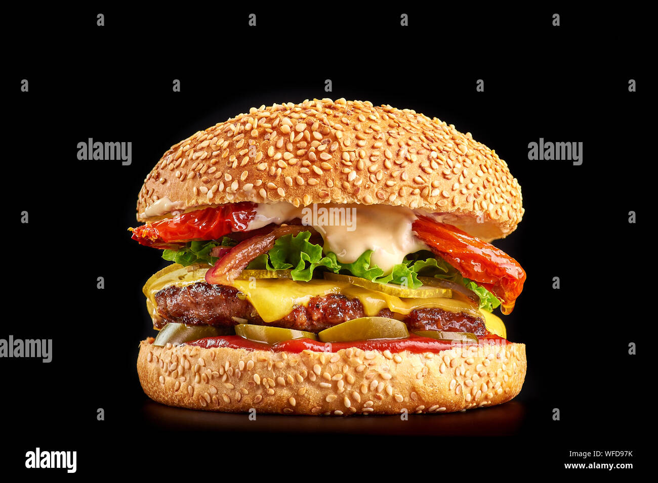 Burger auf schwarzen Hintergrund mit Rind- oder Schweinefleisch Schnitzel oder Steak mit gebratenen Tomaten, Cheddar Käse, Gurken, Salat und Ketchup in Weiß bun w Stockfoto