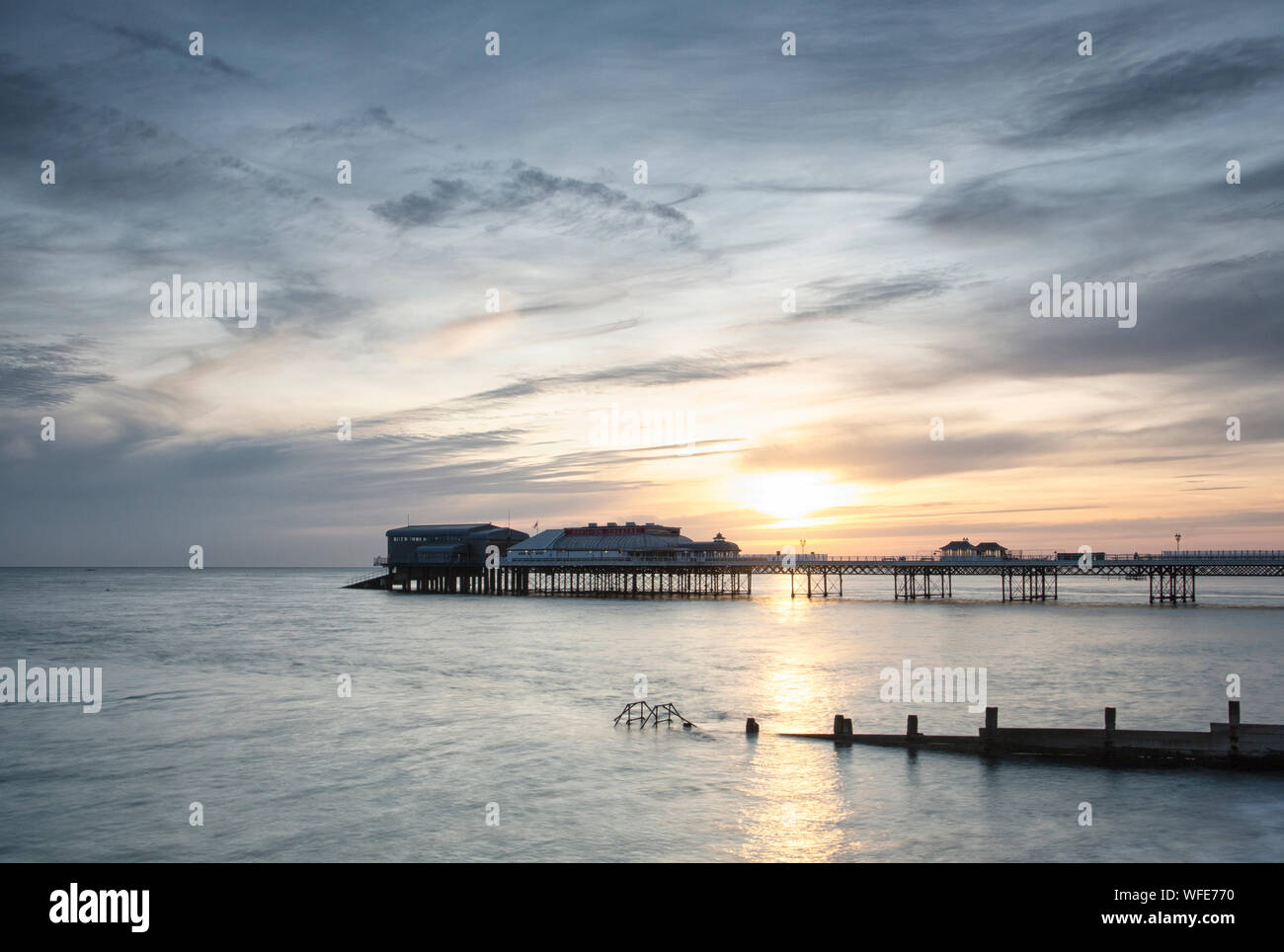 Cromer Pier in der Morgendämmerung und Sunrise mit Regenbogen Farben über den Himmel Stockfoto