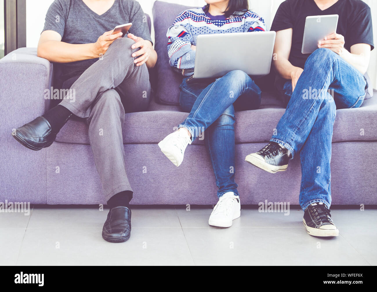 Niedrige Abschnitt Freunden über die drahtlose Technologie beim Sitzen auf dem Sofa Stockfoto