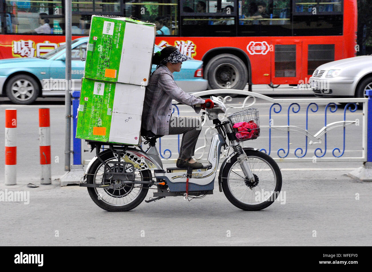 Kurier auf Ihr e-Bike auf den Straßen von Nantong, Jiangsu, China Stockfoto