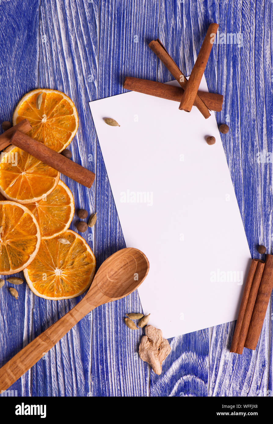 Weihnachtsdekoration. Leer für Rezepte mit getrockneten Orangenscheiben, Zimt und Gewürze auf einem blauen Hintergrund. Ansicht von oben. Stockfoto