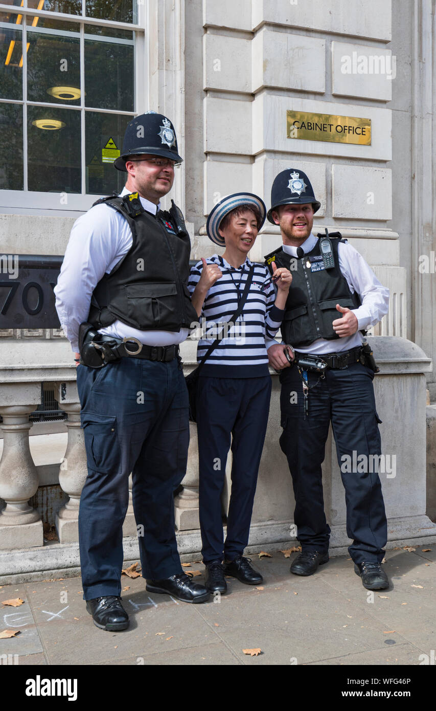 Paar Metropolitan Police Officers für Fotos mit Touristen außerhalb des Cabinet Office in Whitehall, Westminster, London, UK posieren. Polizisten. Stockfoto