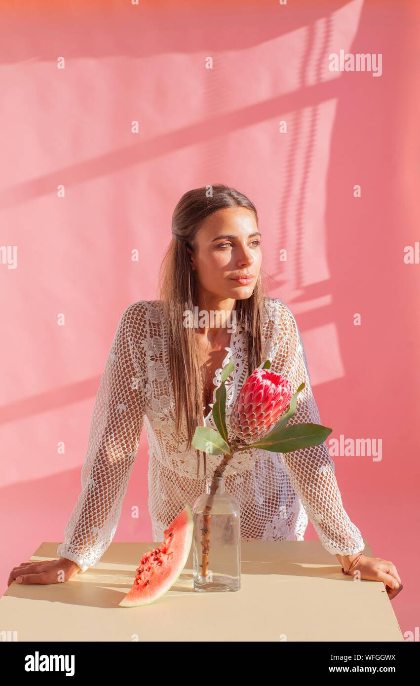 Frau um einen Tisch neben einem Protea Blume und Scheibe Wassermelone Stockfoto