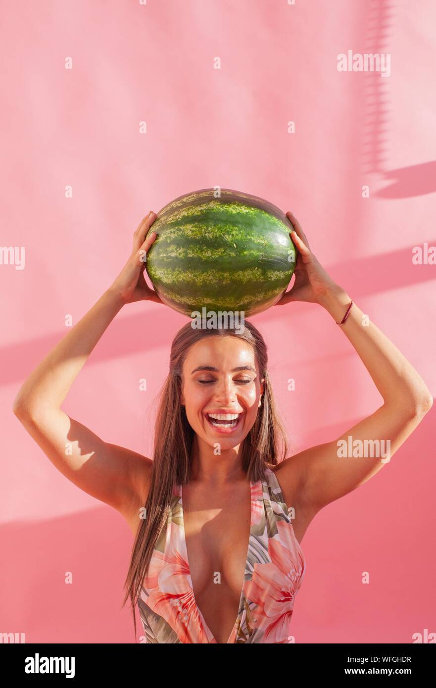 Lächelnde Frau mit einem Wassermelone über ihrem Kopf Stockfoto