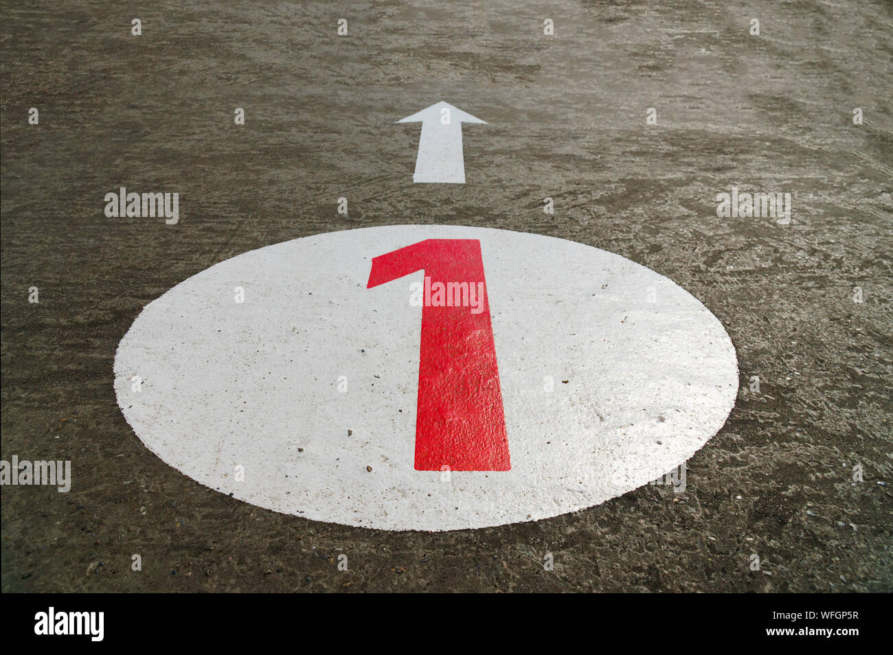 Rote Nummer eins in einem weißen Kreis und einen Pfeil auf konkreten Hintergrund gemalt - 45 Grad Winkel, Nahaufnahme, Querformat Stockfoto