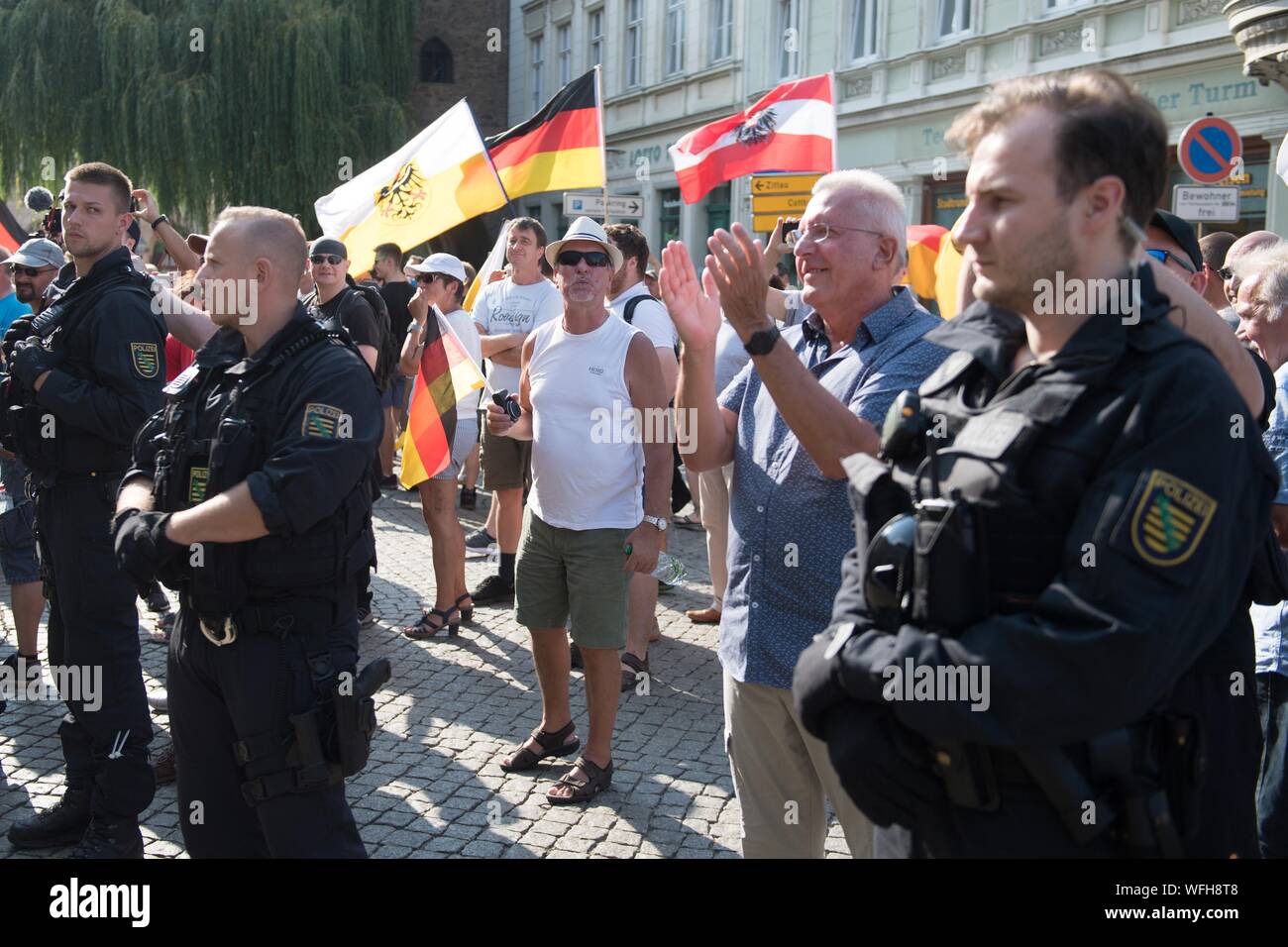 31. August 2019, Sachsen, Görlitz: Teilnehmer einer Demonstration der rechtsextremen Bewegung "Görlitz widersteht" stehen auf der sub-Markt hinter einer Gruppe von Polizisten. Die Rallye findet am selben Tag wie das Ende der Wahlkampf der Sächsischen AfD in der Neiße Stadt. Foto: Sebastian Kahnert/dpa-Zentralbild/dpa Stockfoto