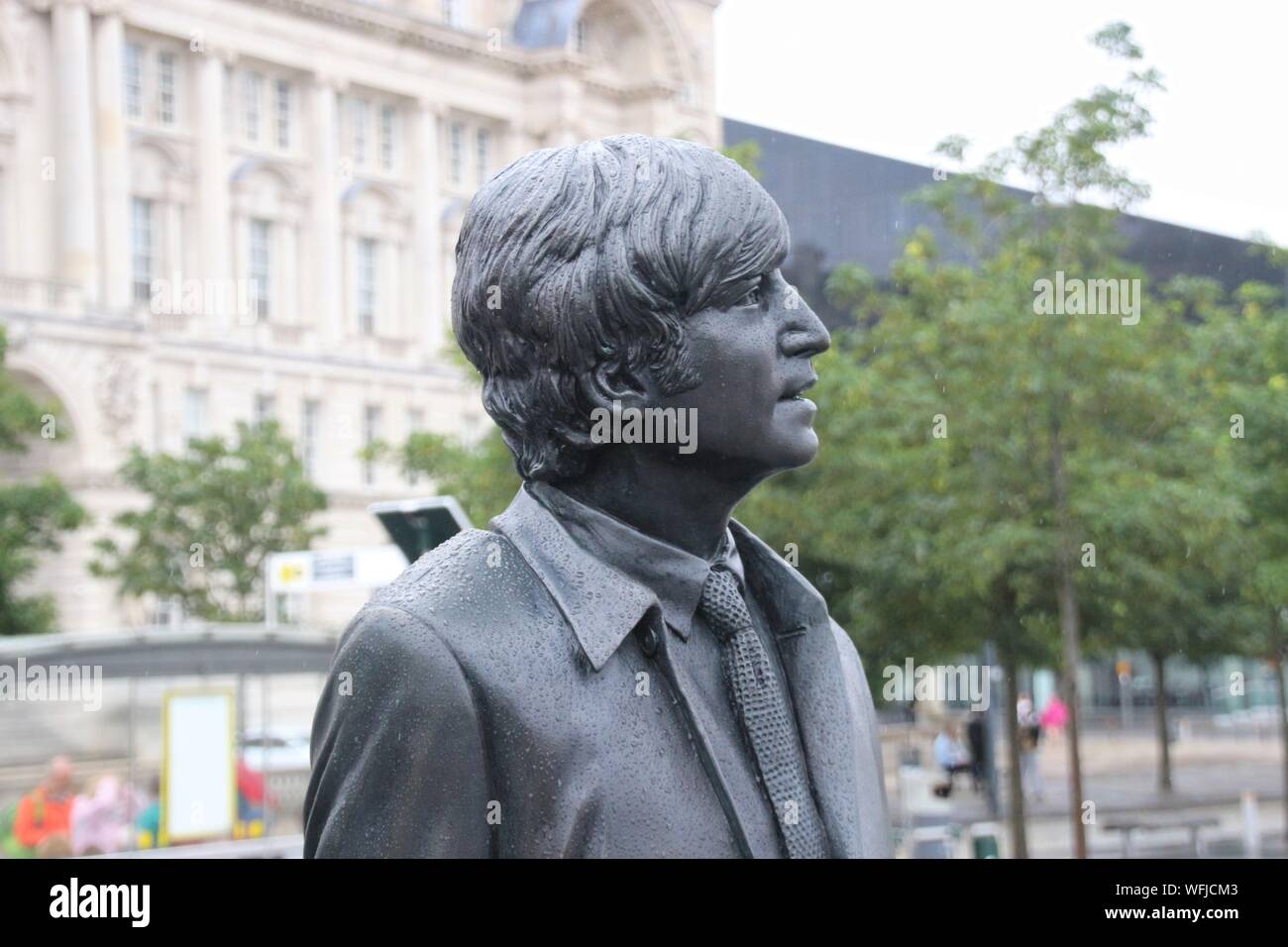Skulptur der Beatles auf Pier Head, Liverpool, England, bei Regenwetter. Detail: Portrait von John Lennon. Artist: Andy Edwards. Europa. Stockfoto