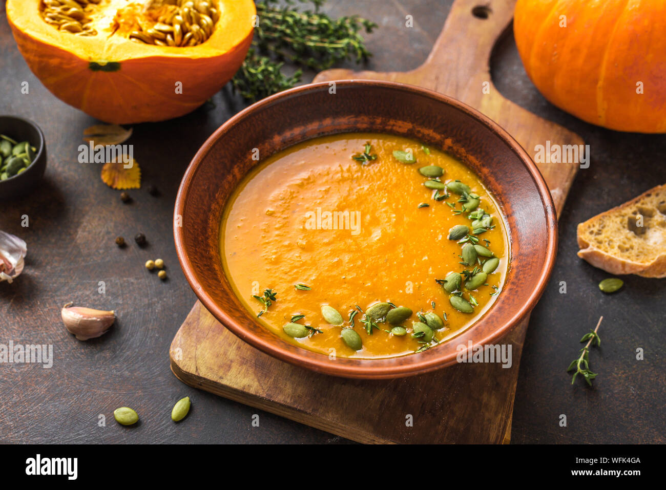 Kürbissuppe und organischen Kürbisse auf rustikalen Holztisch. Saisonale Herbst essen - Würzige Kürbissuppe mit Thymian und Kürbiskernen. Stockfoto