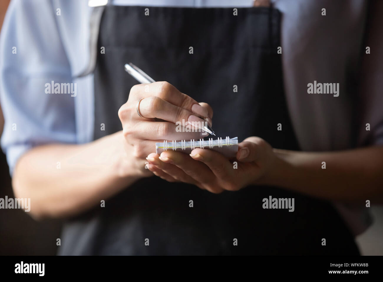 Kellnerin tragen Schürze holding Notizblock Stift Notizen schreiben, um Stockfoto
