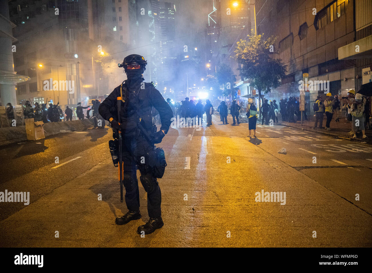 Ein Aufstand Polizist sein Gewehr vor die Demonstranten. Unruhen in Hongkong auch weiterhin als Tausende Demonstranten an einer illegalen Demonstration gegen die Regierung. Benzinbomben wurde von den Demonstranten geworfen worden und feuerte die Polizei mehrere Runden von Gummigeschossen gegen die Demonstranten. Stockfoto