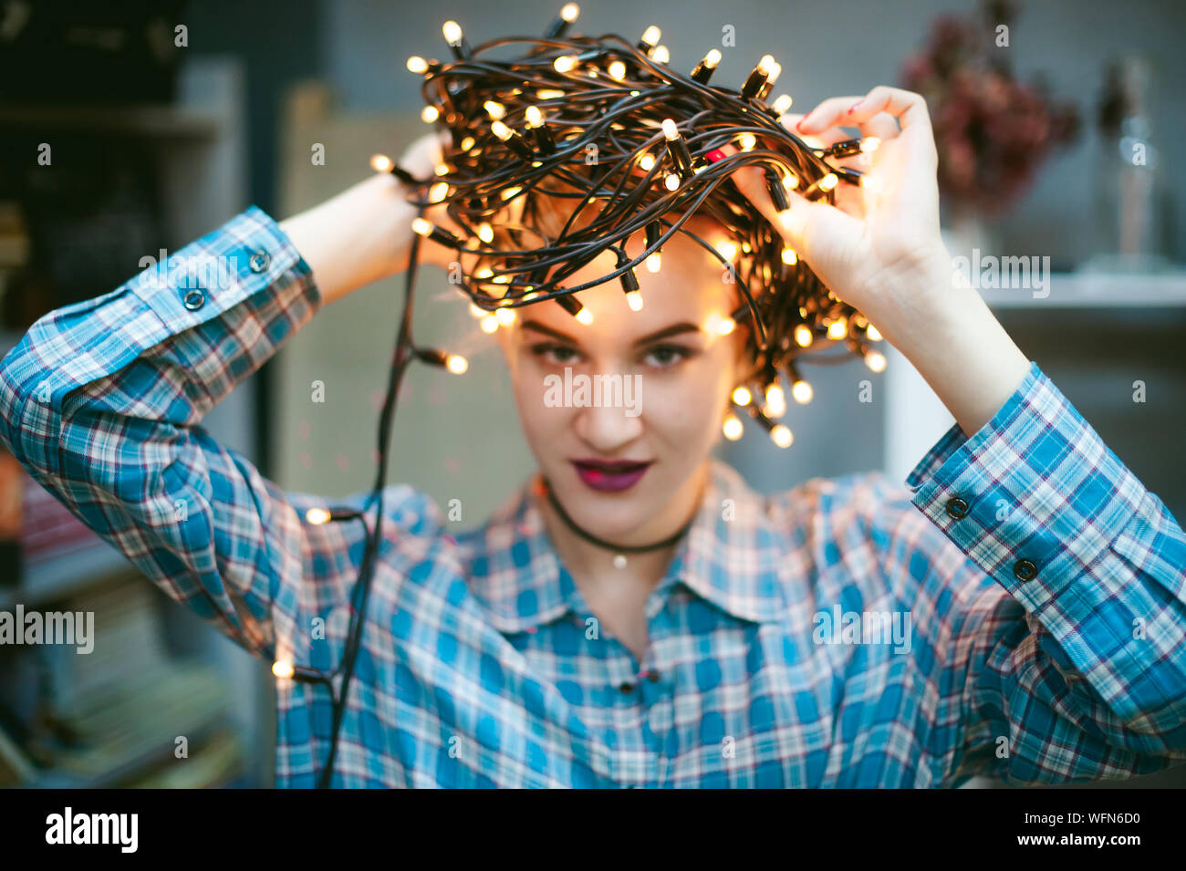 Nahaufnahme Porträt der jungen Frau mit glühenden String Lichter zu Hause Stockfoto