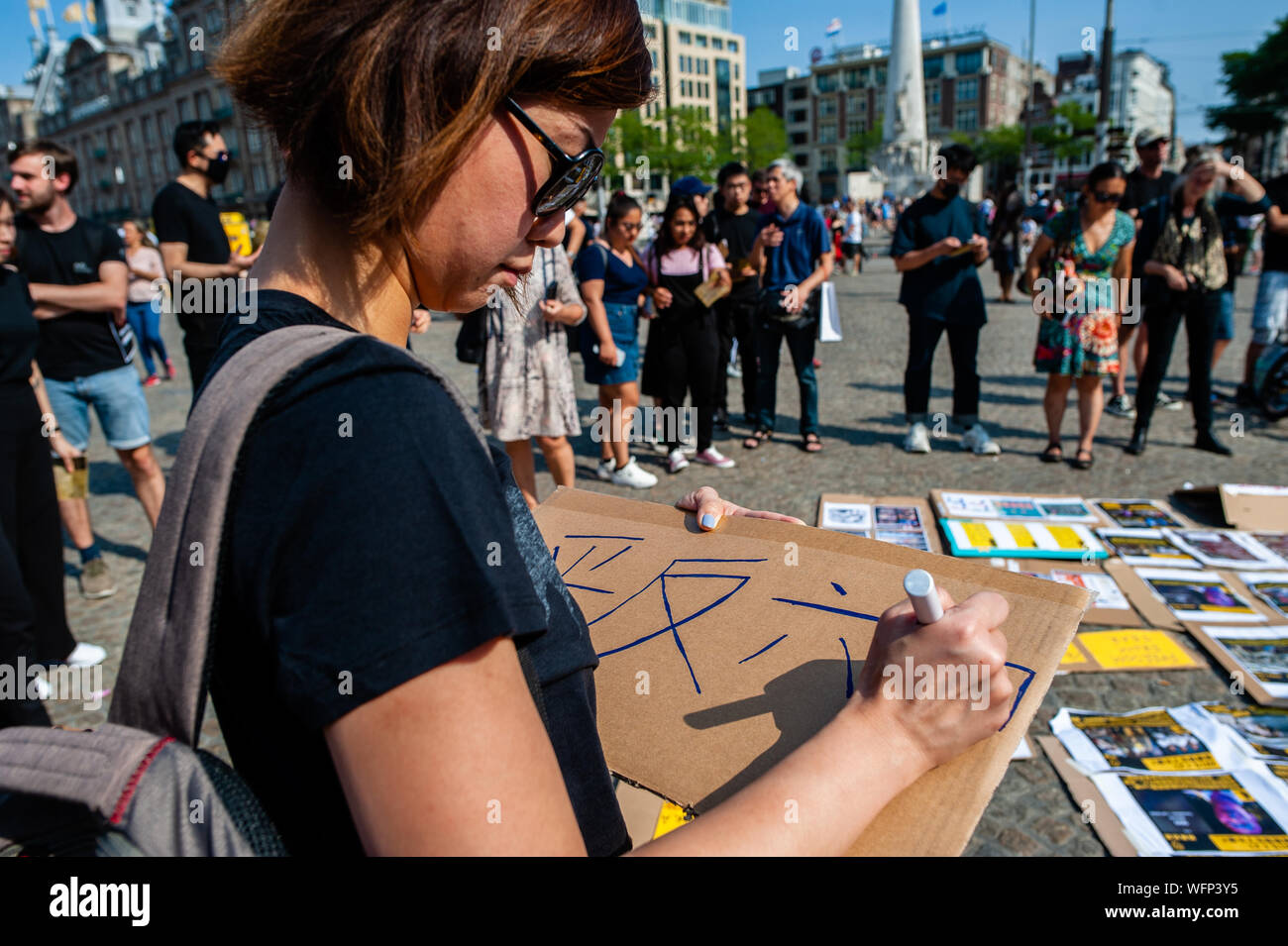 Eine Frau macht ein Plakat während der Demonstration. Menschen versammelt, schwarze Kleidung am Dam Platz tragen protestieren in Solidarität mit den Menschen in Hongkong. Proteste wurden für zwei Monate, über einen jetzt - verschobene Auslieferung Rechnung, aber Nachfragen haben zu Forderungen nach Demokratie und politische Reformen erweitert. Die Regierung von Hongkong hat zu keinen der 5 Forderungen der Menschen in Hongkong reagiert. Stockfoto