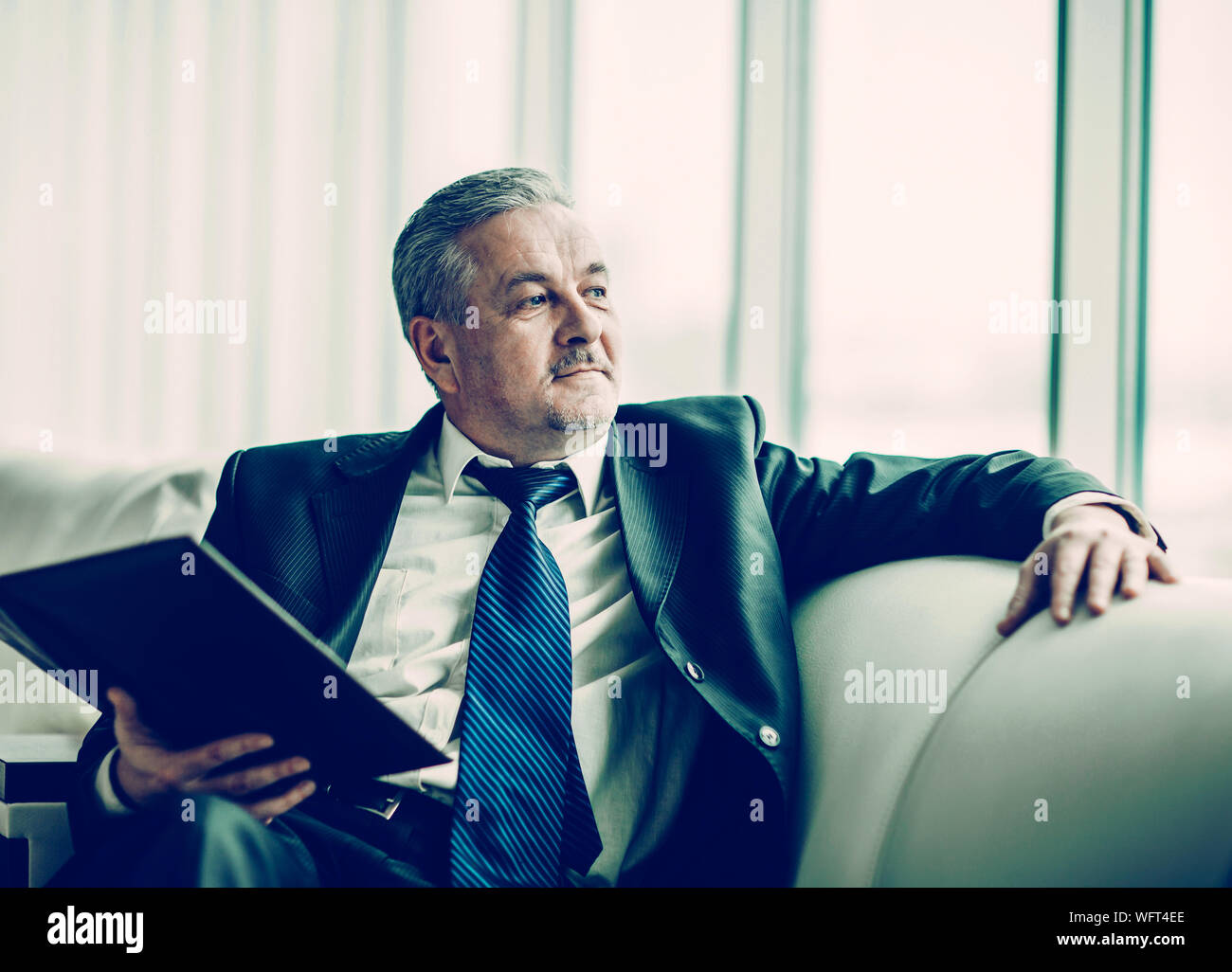 Erfolgreicher Geschäftsmann mit Geschäftsdokumenten sitzen auf einem Sofa in ein eigenes Büro Stockfoto