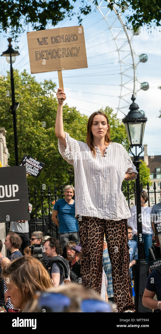 31.Aug 2019 - London, UK. Eine Anti-Brexit Demonstrant hält Banner "Wir fordern Demokratie" außerhalb der Downing Street Gates in Whitehall. Stockfoto