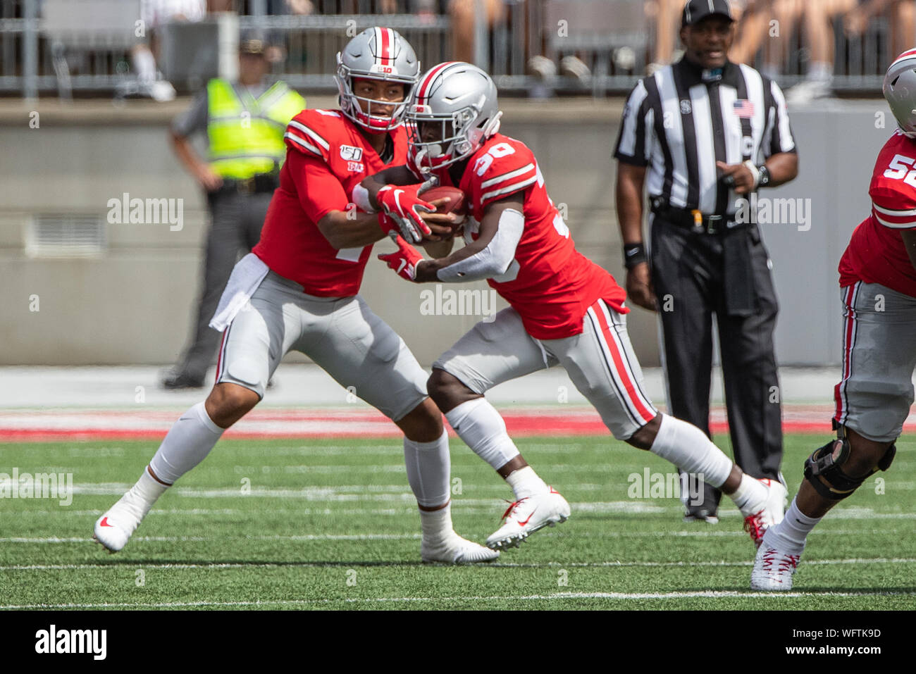 Columbus, Ohio, USA. 31 Aug, 2019. Ohio State Buckeyes Quarterback Justin Felder (1) Hände, die Kugel zu Ohio State Buckeyes zurück laufen Demario McCall (30) in der ersten Hälfte des Spiels zwischen der Florida Atlantic Eulen und die Ohio State Buckeyes am Ohio Stadium, Columbus, Ohio. Credit: Scott Stuart/ZUMA Draht/Alamy leben Nachrichten Stockfoto