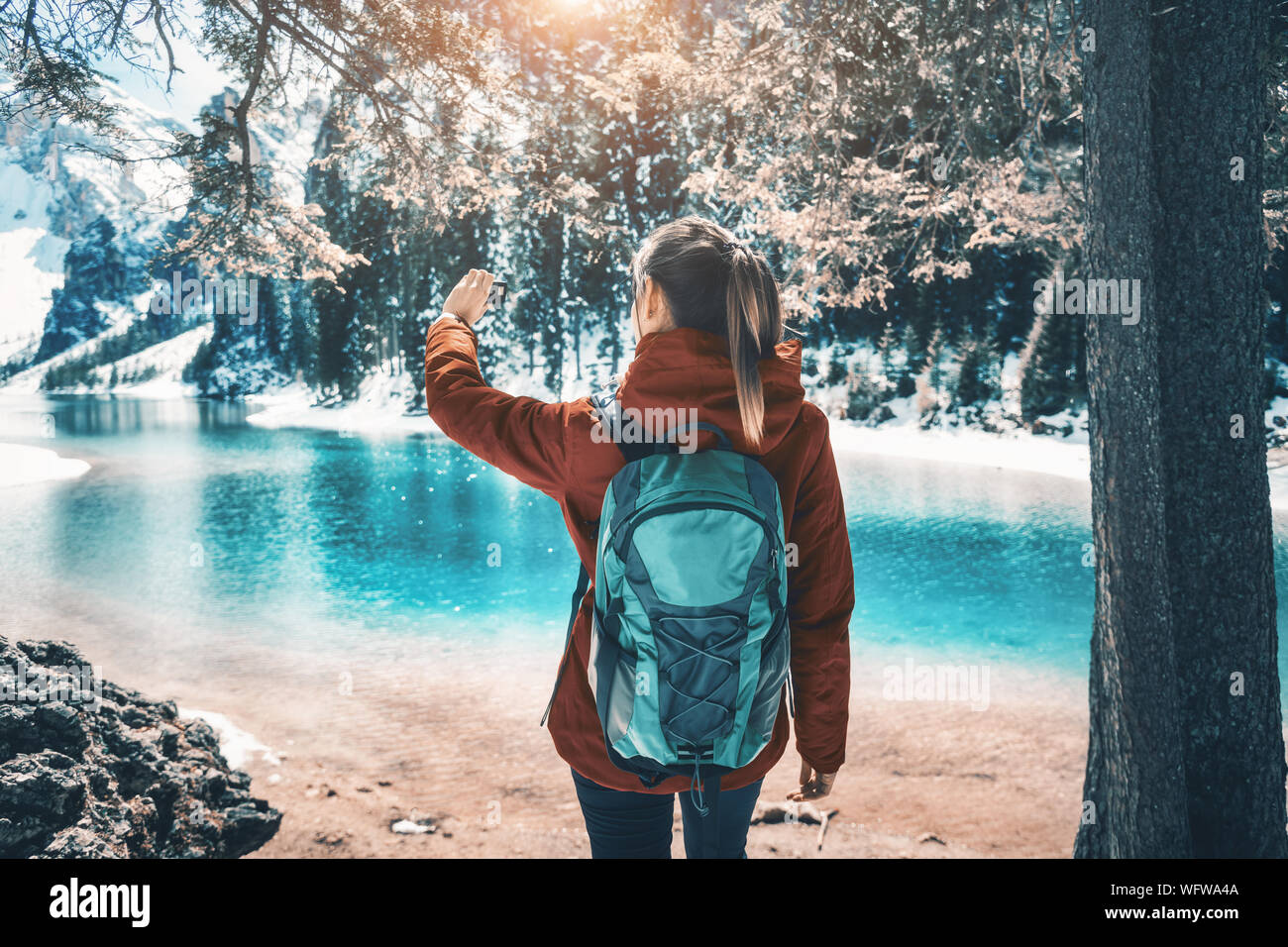 Junge Frau mit Rucksack nimmt ein Selfie auf dem See Bei Sonnenuntergang Stockfoto