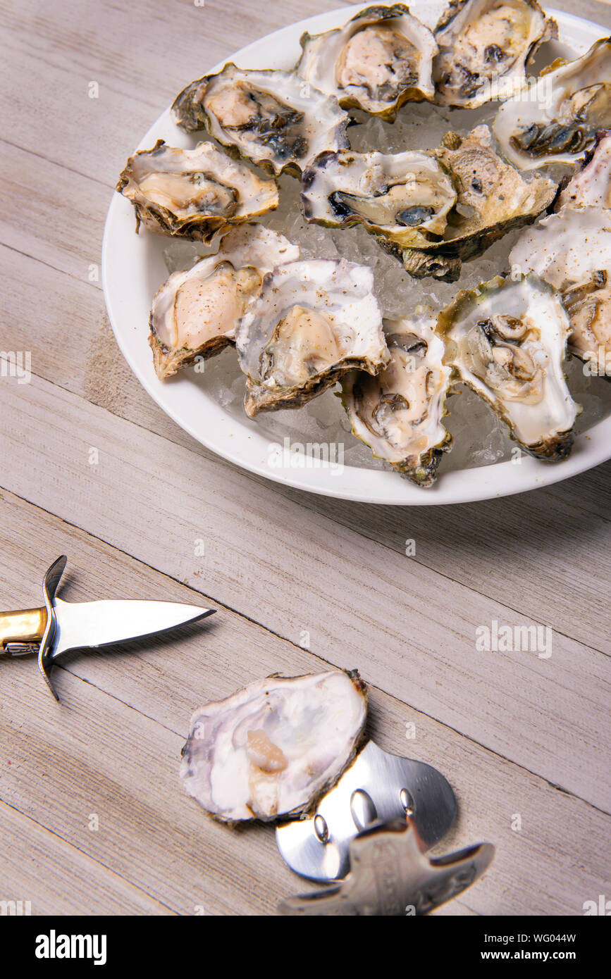 Detail einer Platte mit frischen Spezialitäten Austern aus der kanadischen Westküste über Holz Hintergrund Stockfoto