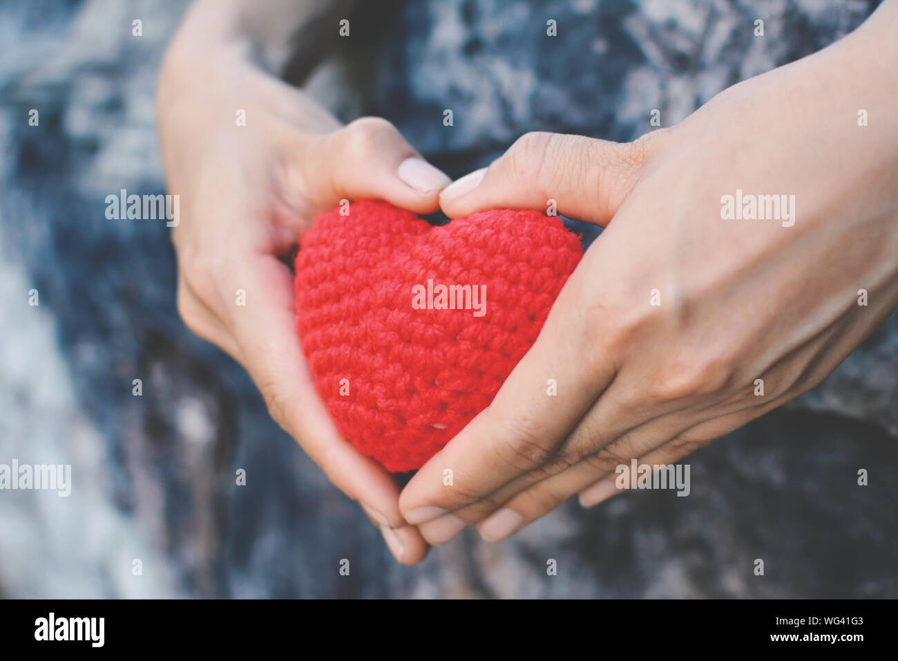 Nahaufnahme der menschlichen Hand gestrickte Herzform Dekoration von Baum im Park Stockfoto