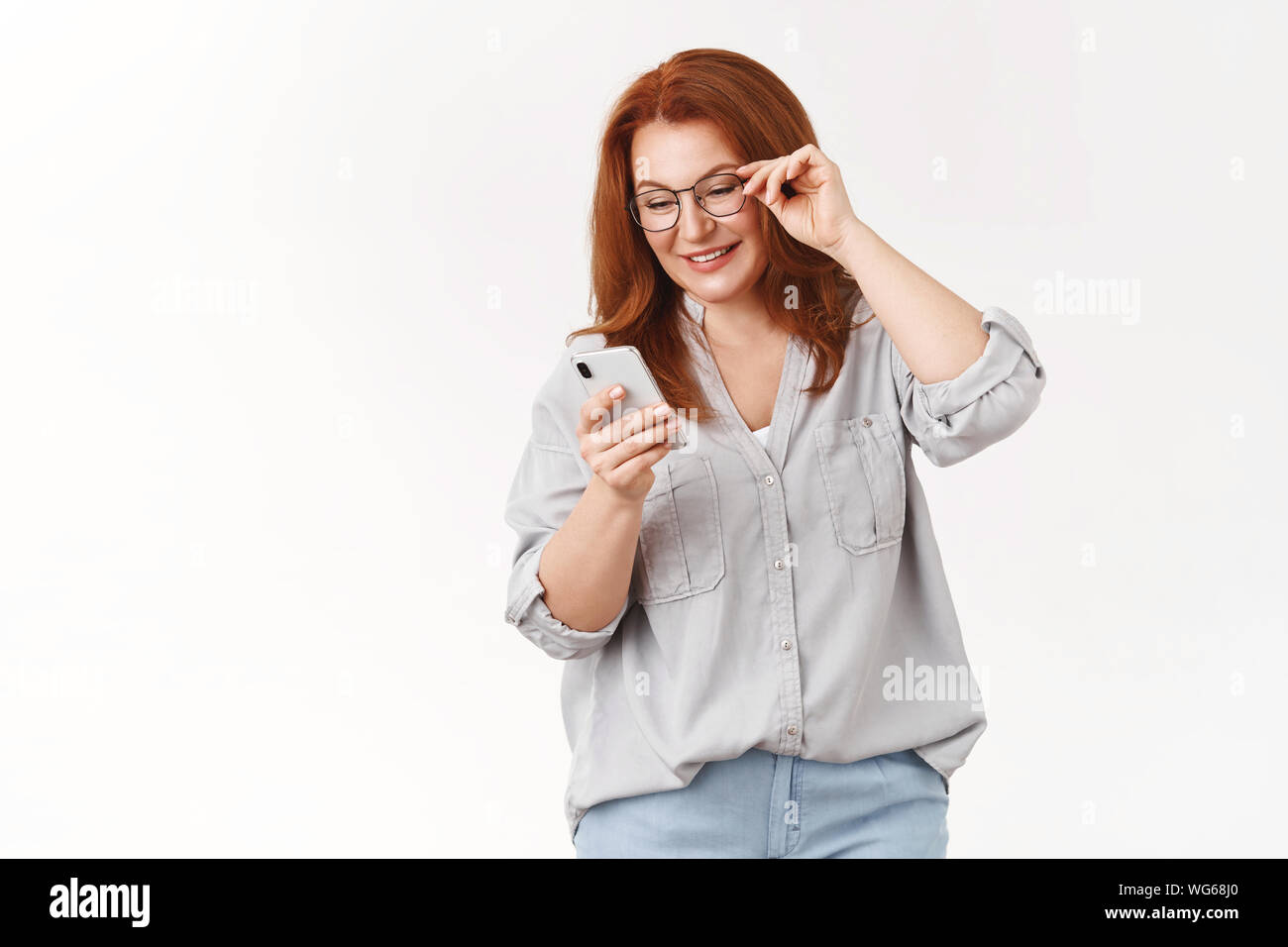 Lassen Sie uns schauen, was wir bekamen. Wunderschöne elegante moderne redhead mittleren Alters mom Brille Nachricht lesen Sie Sohn senden Fotos social media suchen Smartphone Stockfoto