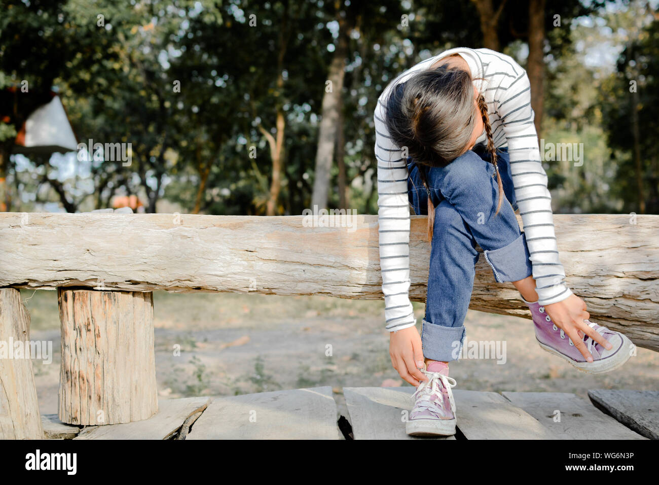 Volle Länge des Mädchens biegen beim Sitzen auf Holz- Log Stockfoto