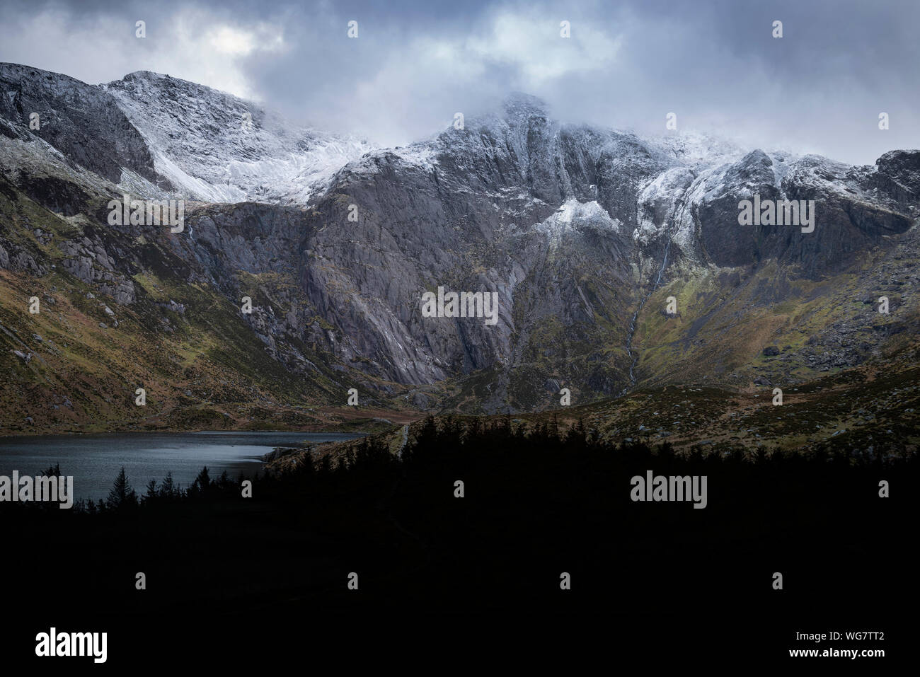 Atemberaubende dramatische Winterlandschaft Bild von Llyn Glyders Idwal und schneebedeckten Bergkette in Snowdonia Stockfoto