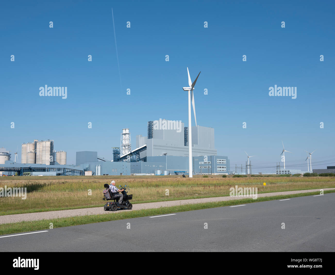 Alter Mann in Scoot mobile übergibt Industrie eemshaven an sonnigen Sommertagen Stockfoto