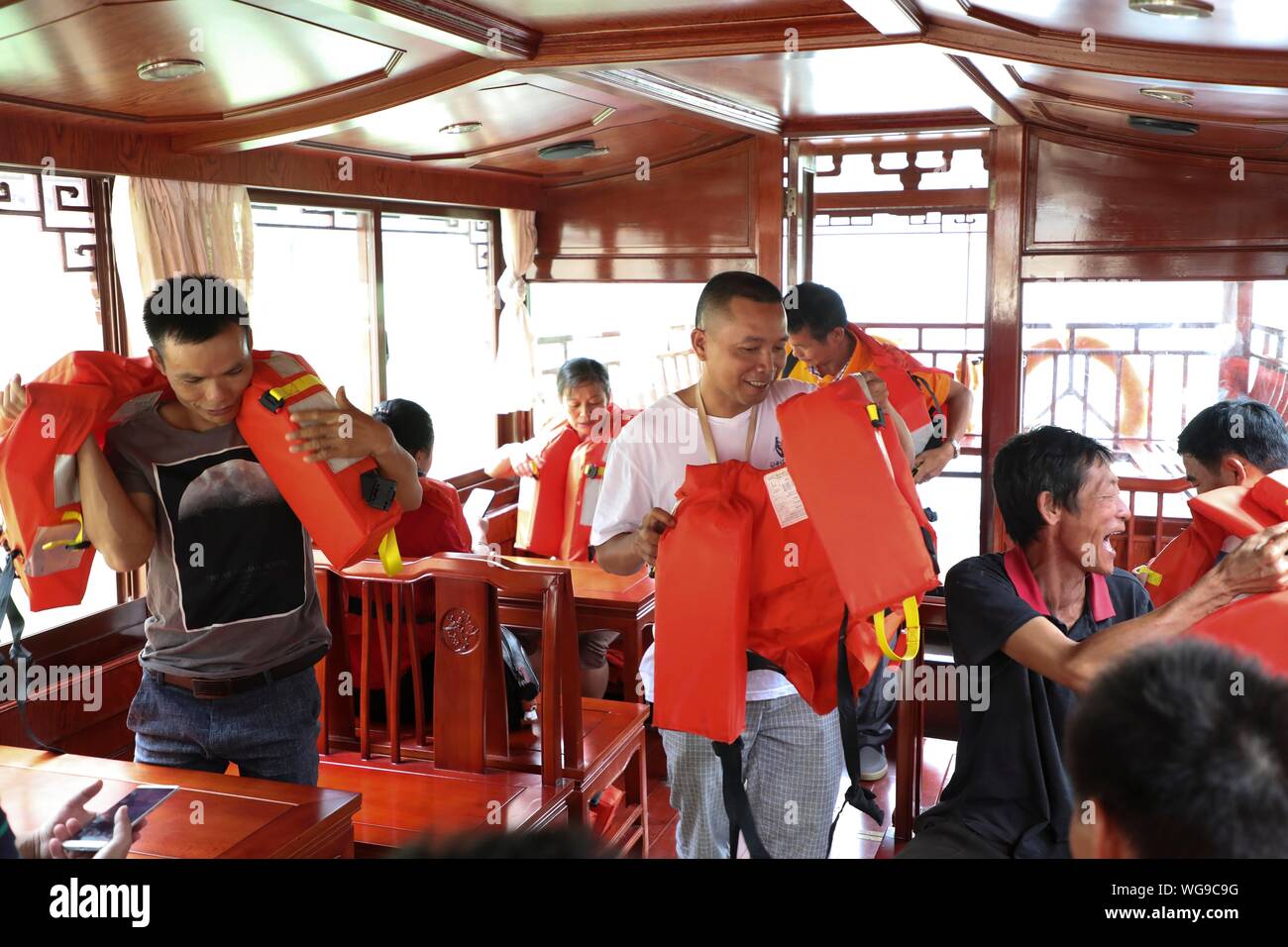 (190901) - LINGYUN, Sept. 1, 2019 (Xinhua) - Lao Ketuan Hände Schwimmwesten für Touristen an der Haokun Lake Scenic Spot in Lingyun County, South China Guangxi Zhuang autonomen Region, Aug 31., 2019. Lao Ketuan, 40, lebt in den gebirgigen Dorf Haokun, einem Ort mit extrem schlechten Transport und knappen Landressourcen, die ernsthaft in die lokale Entwicklung behindert und die Menschen hier in Armut gefangen. Der laotische Familie ist unter den verarmten Haushalte, die hier leben. 2016, Lao hatte jedoch nie träumen lassen, dass seine Familie aus der Armut erhalten konnten dank der lokalen Behörden arbeiten o Stockfoto