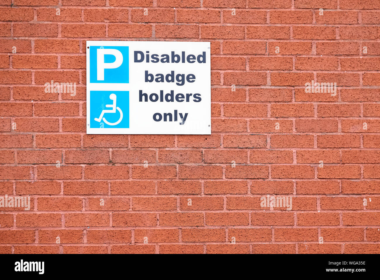 Deaktiviert blau Badgeholder nur Zeichen auf orange brick wall Stockfoto