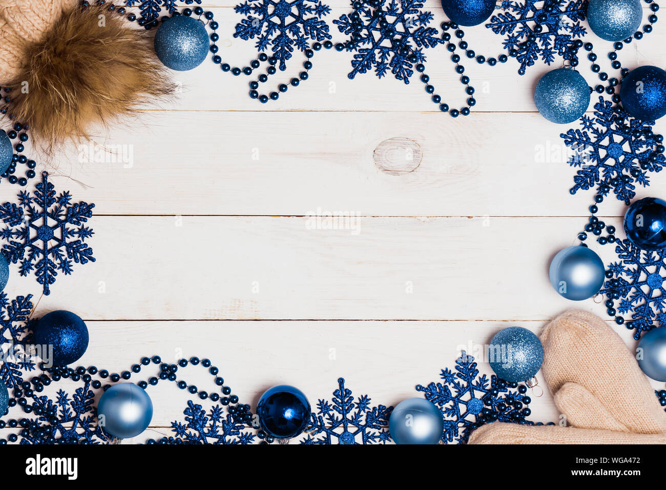 Schöne Weihnachten Rahmen blau glänzende Verzierungen, gestrickte warme Mützen und Handschuhe auf weißem Holz- Hintergrund mit Kopie Platz für Text und Werbung Stockfoto