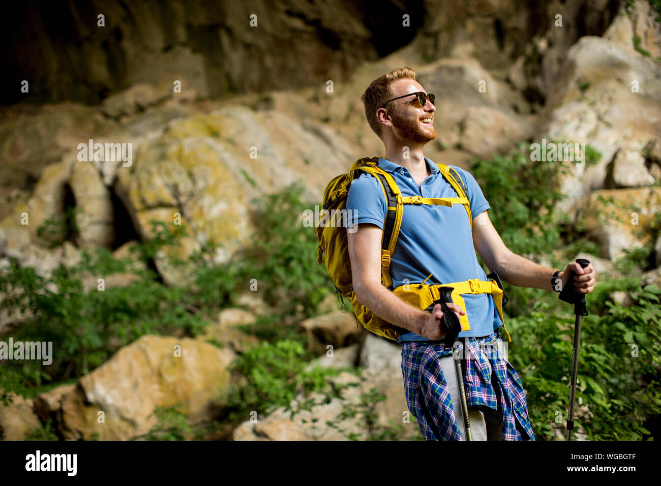 Anmutige junge Kaukasier Männlich Wanderer mit Rucksack wandern an einem sonnigen Tag Stockfoto