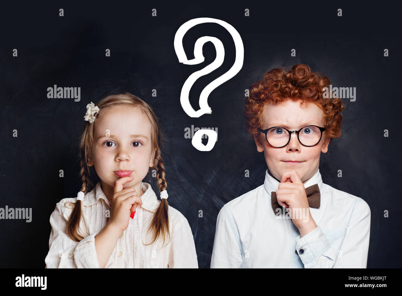 Intelligentes Denken kleines Mädchen und jungen Schüler mit Fragezeichen auf blackboard Hintergrund. Brainstorming und Idee, Konzept Stockfoto