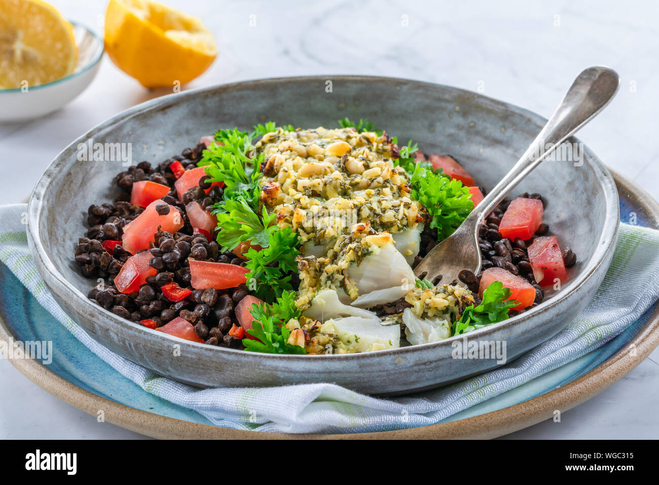 Pesto - verkrusteten Kabeljau mit Puy Linsen und Tomaten in eine Schüssel geben. Stockfoto