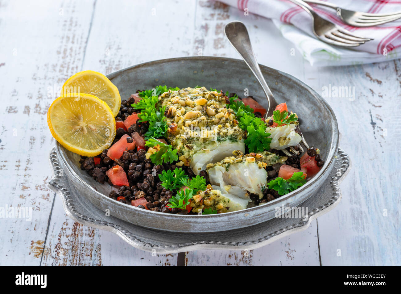 Pesto - verkrusteten Kabeljau mit Puy Linsen und Tomaten in eine Schüssel geben. Stockfoto