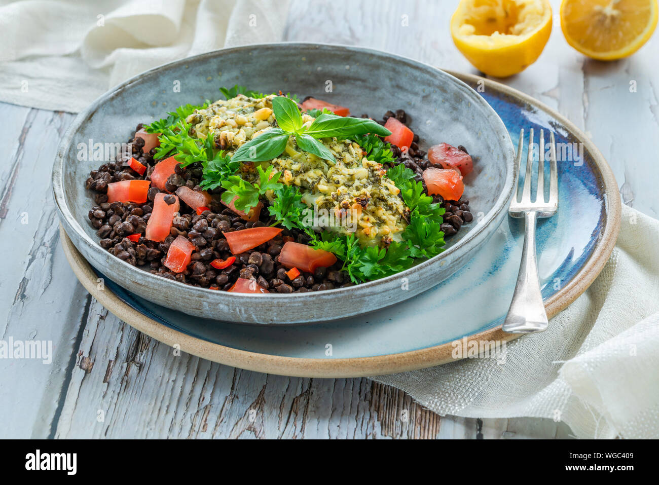 Pesto - verkrusteten Kabeljau mit Puy Linsen und Tomaten in eine Schüssel geben. Stockfoto