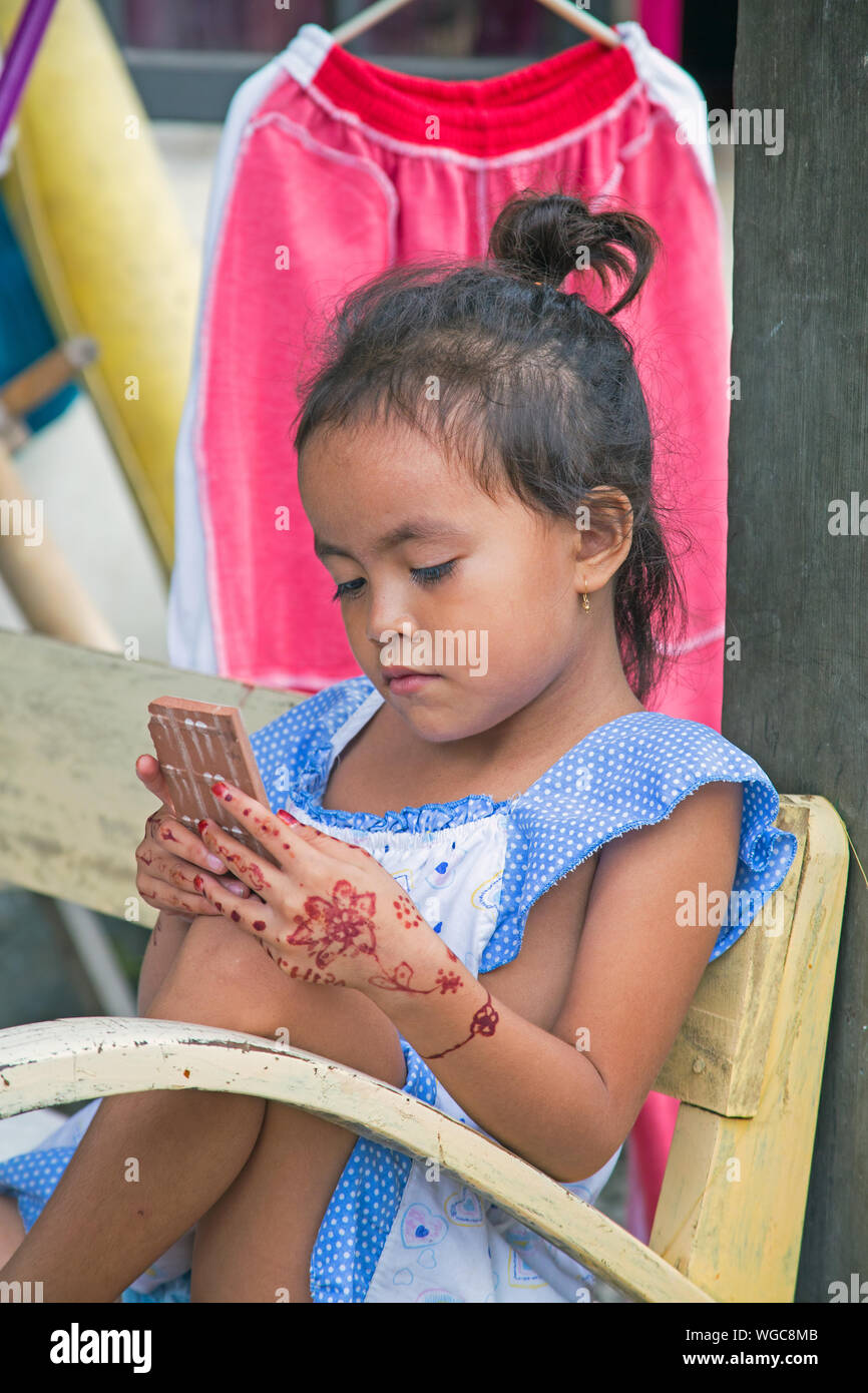 LOMBOK, Indonesien - 30. Dezember 2016: Schöne junge Mädchen spielend auf ihrem Handy in Lombok, Indonesien am 30. Dezember 2016 Stockfoto