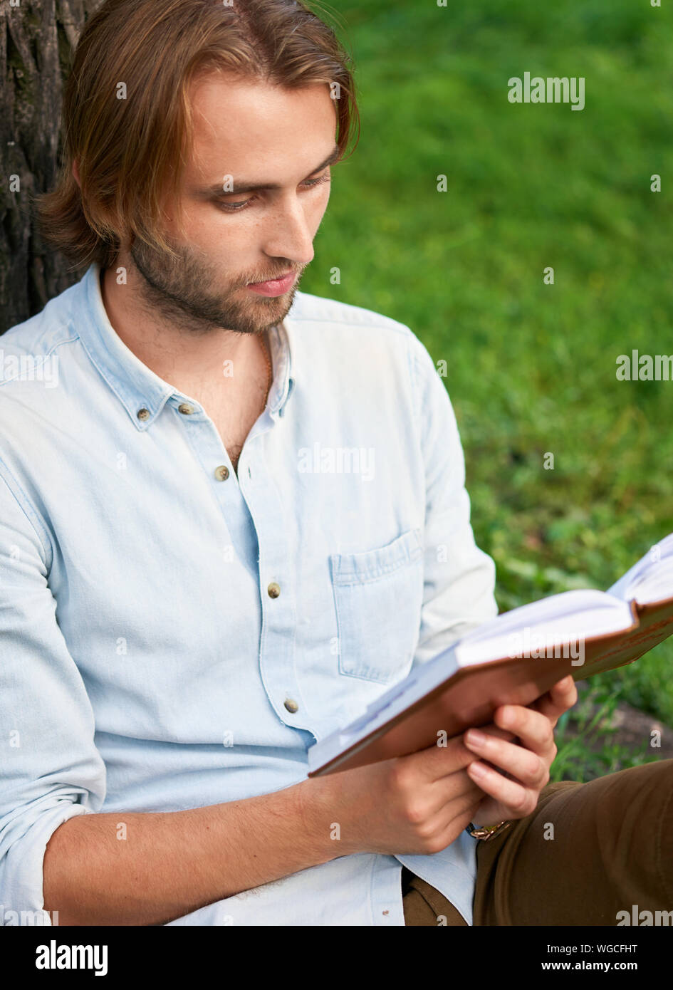 Ernster Kursteilnehmer im Park Campus ein Buch lesen. Stockfoto