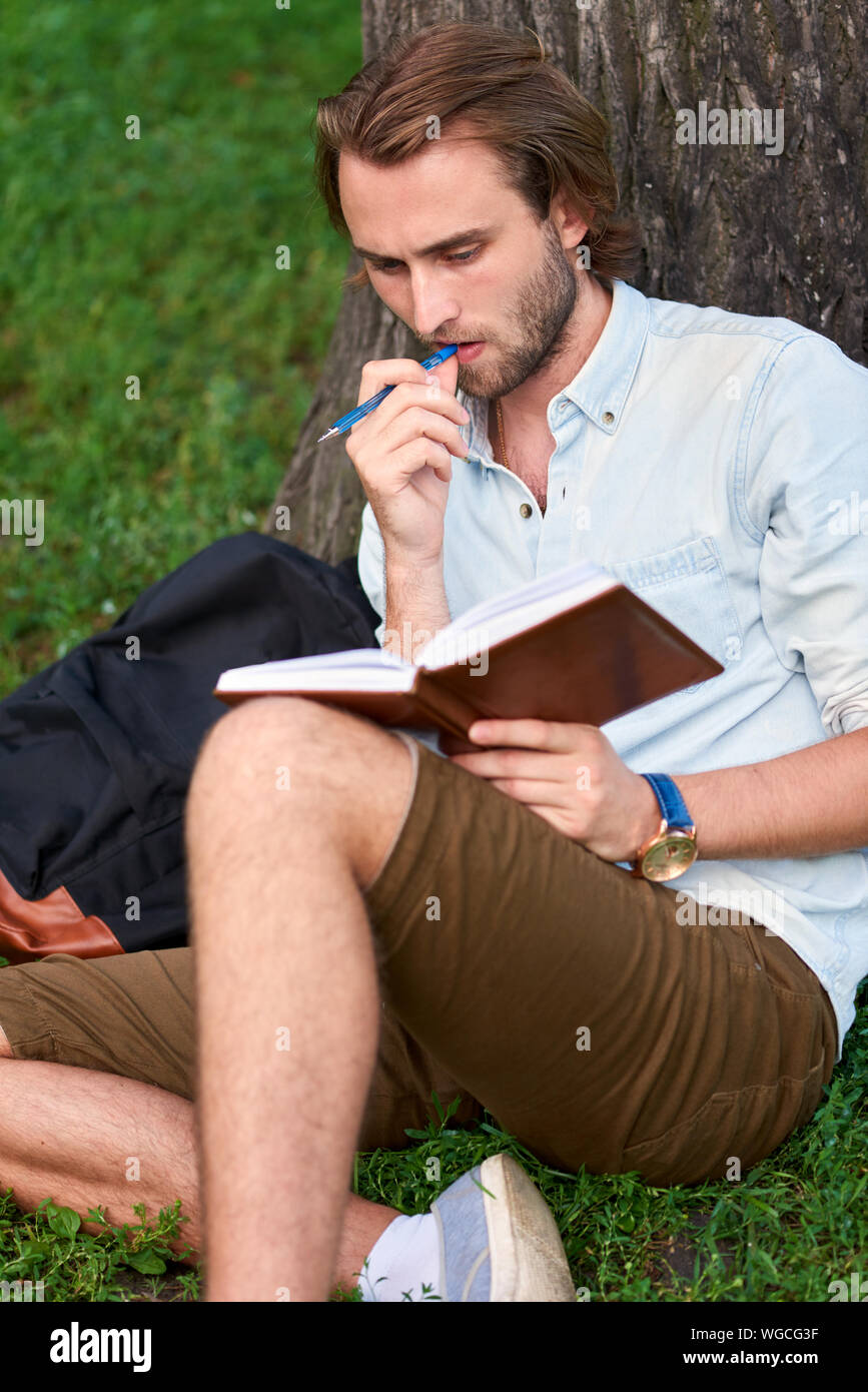 Ernster Kursteilnehmer im Park Campus ein Buch lesen. Stockfoto