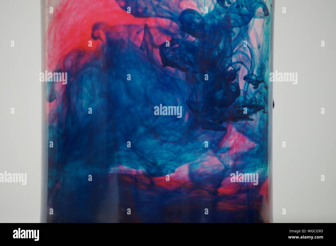 Close-up von Farben gemischt im Wasser vor weißem Hintergrund Stockfoto