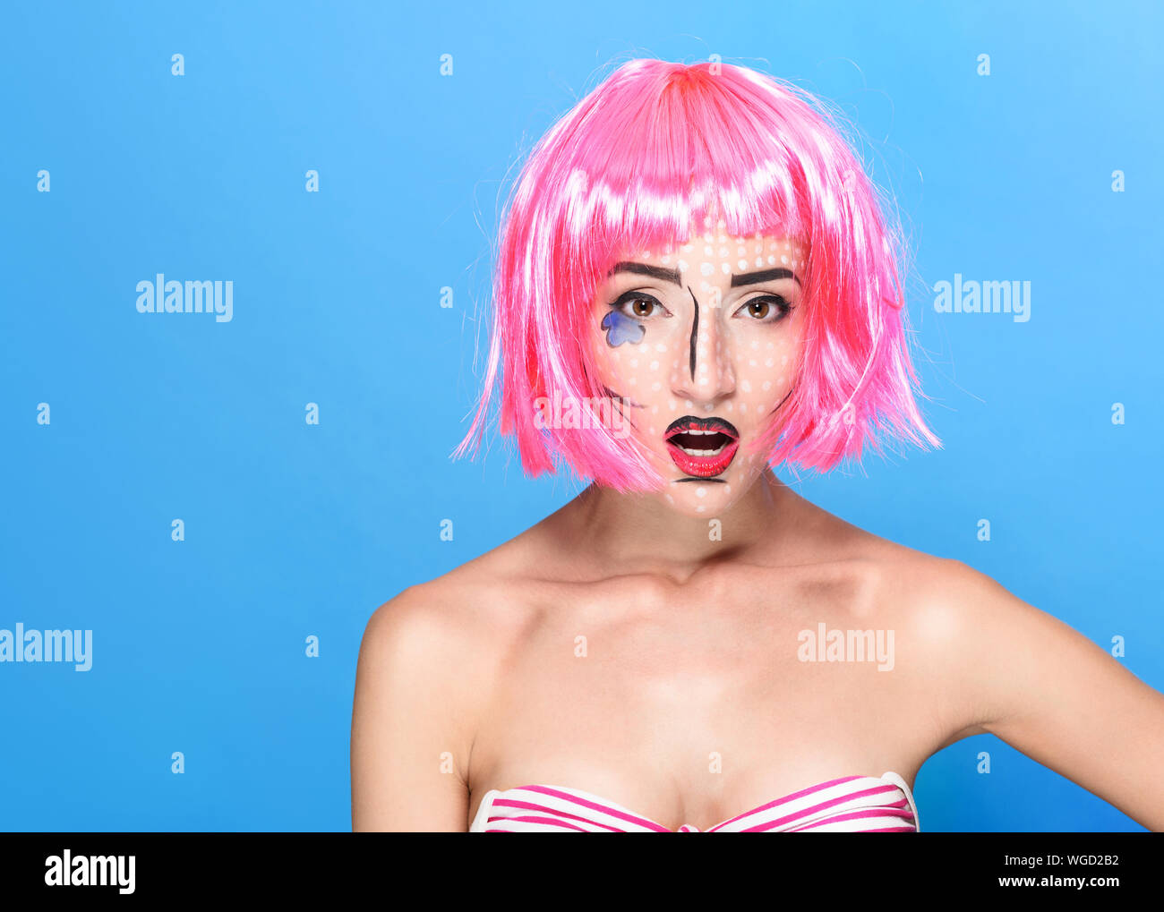 Beauty Kopf schoss. Überrascht junge Frau mit kreativen Pop Art bilden und rosa Perücke mit Blick auf die Kamera auf blauem Hintergrund. Stockfoto