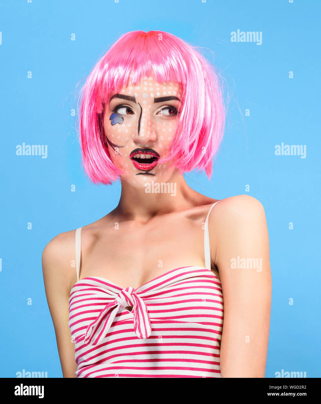 Beauty Kopf schoss. Überrascht junge Frau mit kreativen Pop Art bilden und rosa Perücke mit Blick auf die Kamera auf blauem Hintergrund. Stockfoto