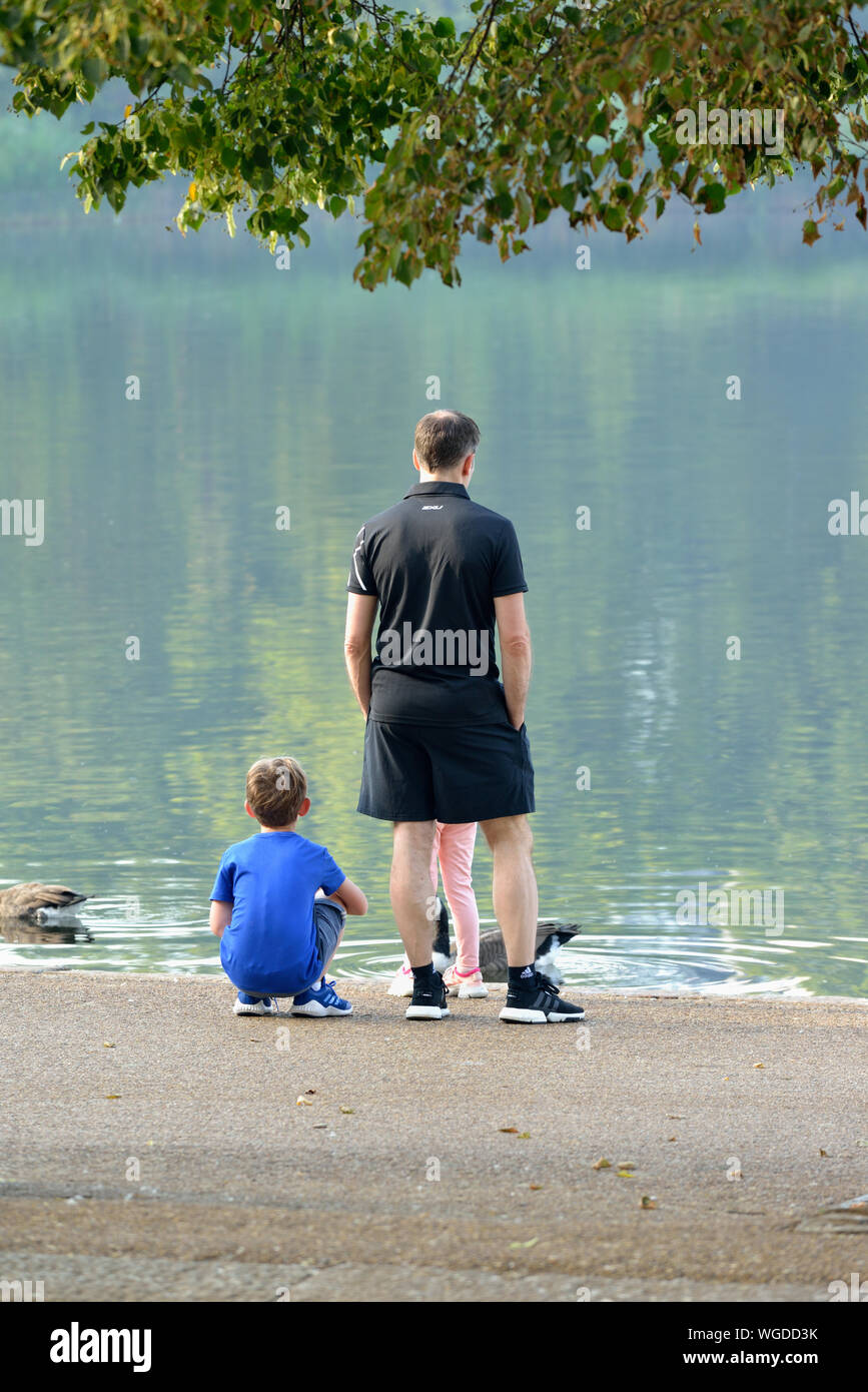 Junge Familie Füttern der Vögel auf See Serpentine Lake, Hyde Park, London, Vereinigtes Königreich Stockfoto