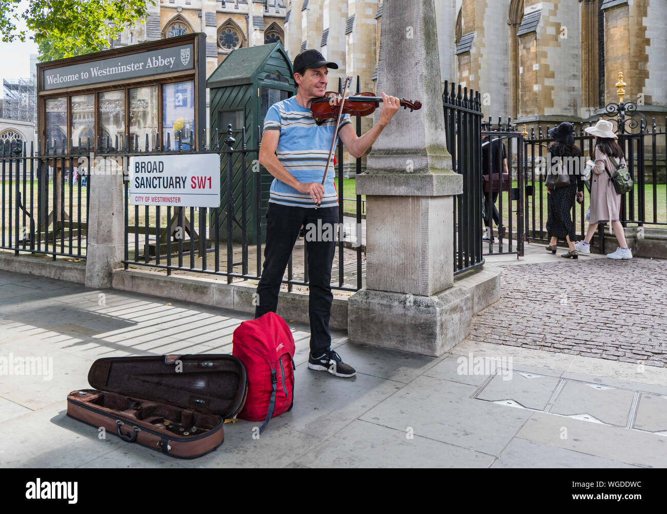 Street Entertainer, Straßenmusiker oder Gaukler Spielen der Violine, Straßenmusik außerhalb der Westminster Abbey in Westminster, London, England, UK. Geiger. Stockfoto