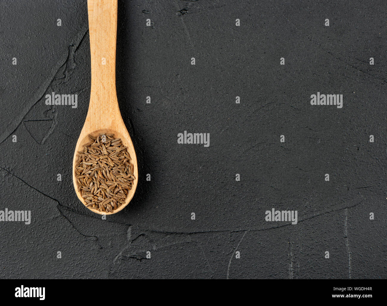 Kleine Löffel mit trockenen Kreuzkümmel auf Leeren dunklen Hintergrund Stockfoto
